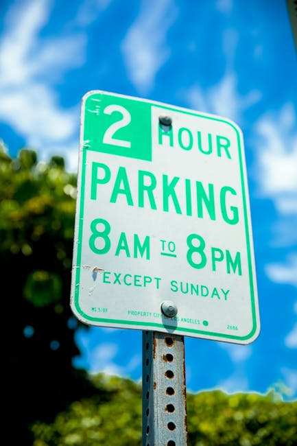 A close-up photograph of a rectangular white parking sign mounted on a wooden post outside a building, indicating parking for blue badge holders with a blue wheelchair symbol and the text 'Blue badge 